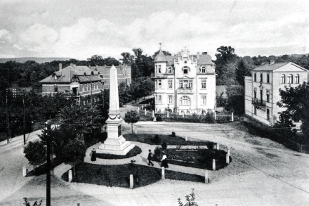 Der Georgsplatz 1909. Links die Villen von August Mller und Armin Trunk in der Frbelstrae. Mittig die Villa Roseneck. Rechts das lteste Haus am Platze. Der sich im Bild befindliche Seitenflgel ist 1888 von Pfarrer de Harde als Pfarreigebude errichtet worden. Neben dem Haus ist der stliche Zacken des Platzes deutlich sichtbar. Im Vordergrund das Denkmal mit den beiden sdlich verlaufenden Wegen, die auf die Breite der Georgstrae ausgerichtet sind. - Bildautor: Sammlung Dieter Klotz